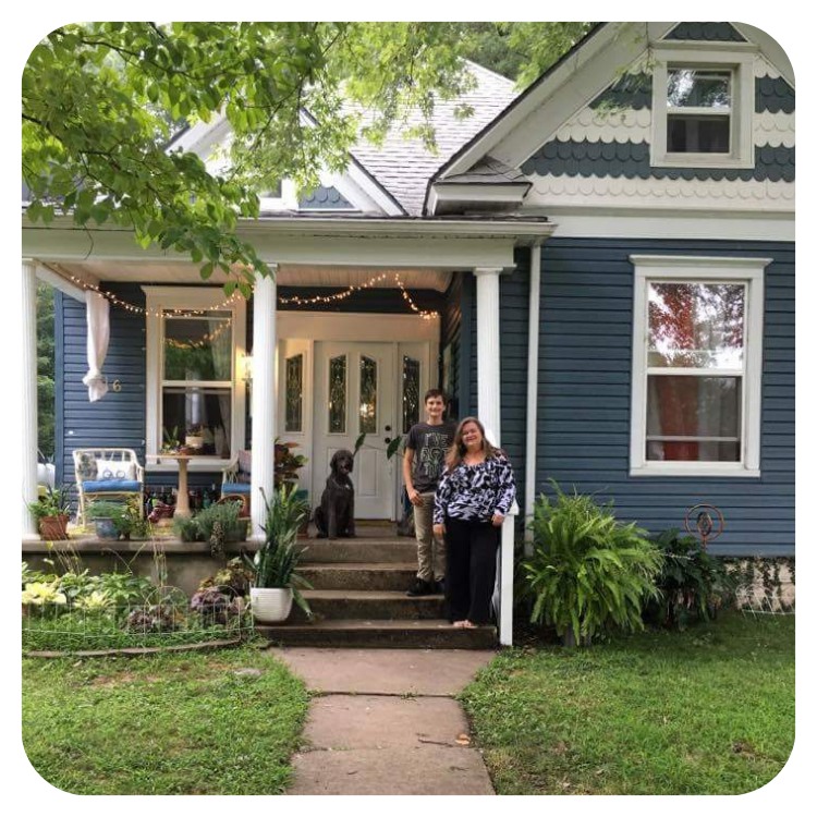 Couple who purchased a home through the Springfield Community Land Trust standing on the front porch of their new home