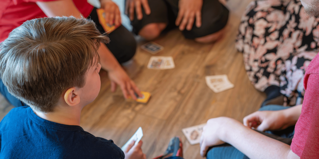 Family playing cards together in the home they purchased with Springfield Community Land Trust