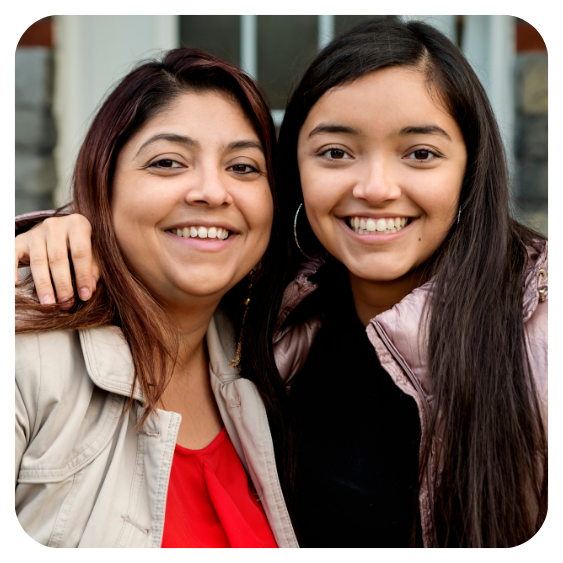 Mother smiling with teenage daughter in front of the house they purchased through the Springfield Community Land Trust